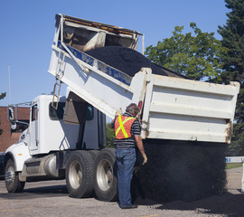 Workman dumping asphalt for pothole repairs; Edmonton, Alberta, Canada