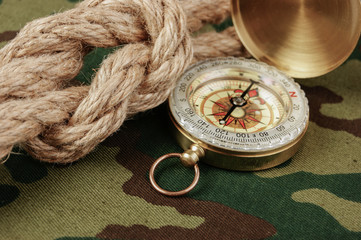 Fototapeta na wymiar Compass and rope on a camouflage background