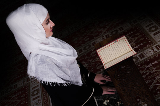 Beutiful muslim woman reading Koran in mosque