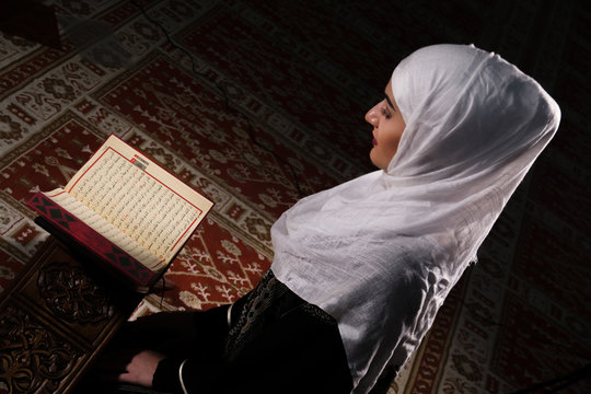 Muslim woman in mosque reading Koran, Reading Koran