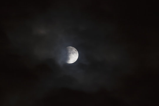 Lunar eclipse, viewed through passing clouds; Brampton, Ontario, Canada