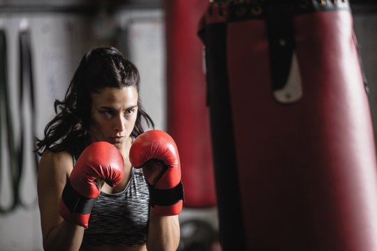 Female boxer practicing boxing with punching bag