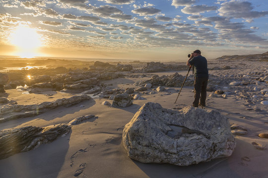 Man photographing sunset at Marble Beach, South Africa
