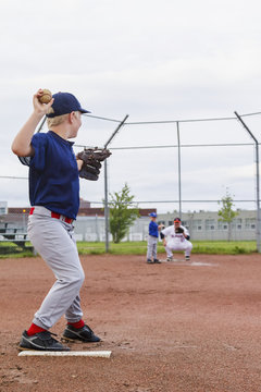 A young boy in his baseball uniform prepares to throw a pitch to his brother at bat; Fort McMurray, Alberta, Canada