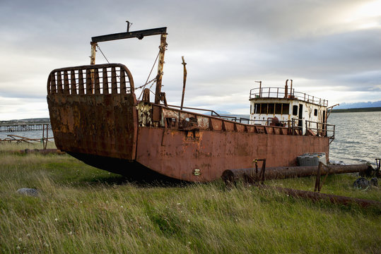 Old fishing boat on the grass shore; Natales, Magallanes and Antartica Chilena Region, Chile