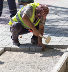 Worker puts sidewalk tile on the road