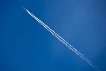 Airplane in a blue sky with traces