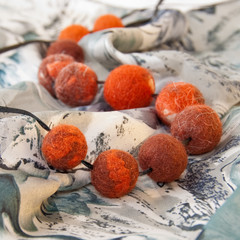Handmade stylish warm felt necklace on scarf. Shallow depth of field. Focus on the closest beads.