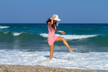 Naklejka na ściany i meble Beautiful carefree woman in short pink dress at the beach.