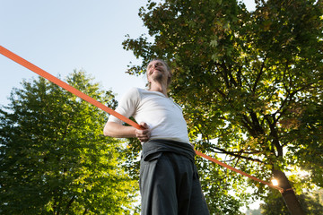 Guy practising slack line in the city park