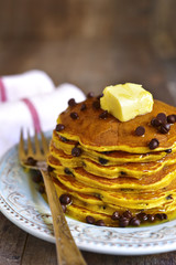 Pumpkin pancakes with chocolate drops on a rustic background.