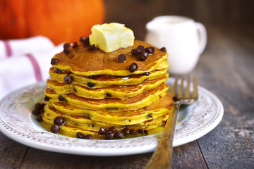 Pumpkin pancakes with chocolate drops on a rustic background.