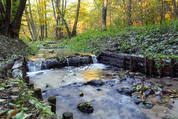 Small waterfall on a river in the forest. Autumn landscape. Long exposure.