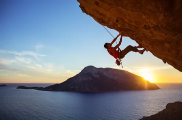 Fotobehang Mannelijke klimmer op overhangende rots tegen prachtig uitzicht op de kust hieronder © Andrey Bandurenko