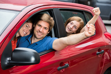 Family Sitting In Car Raising Their Arms