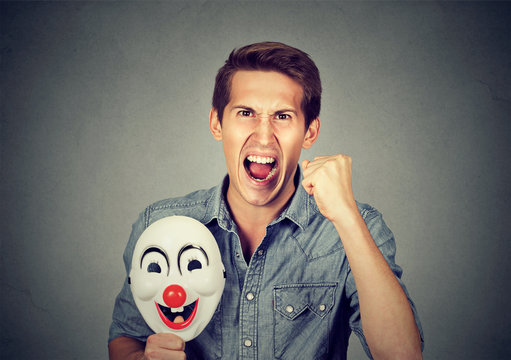 angry screaming man holding clown mask expressing cheerfulness