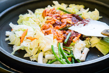 One of Korean favorite : Korean spicy stir fried vegetable, chicken and Korean spicy sauce (Gochujang) in big hot pan know as Dak Galbi