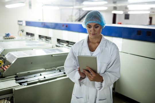 Female staff using digital tablet next to production line