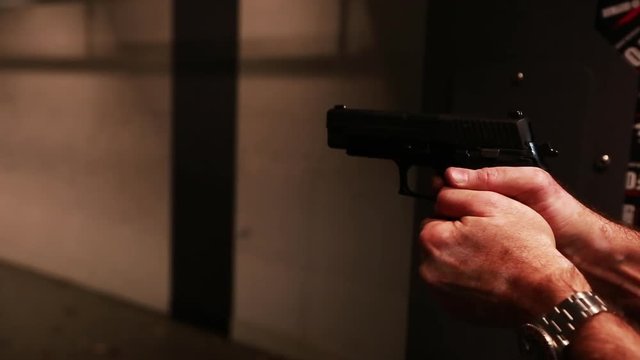 Indoor gun range, close up, man fires multiple shots from handgun.