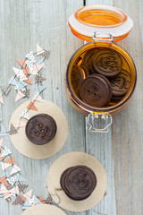 Fototapeta na wymiar Halloween chocolate cookies with jack-o-lantern cut outs. Orange glass jar filled with cookies. 
