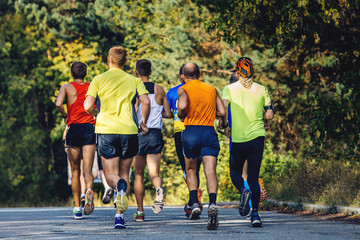 groep hardlopers marathonlopers om in de herfst op asfalt te rennen Park.gele bladeren aan bomen