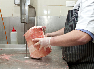 Butcher cutting meat with a Band saw
