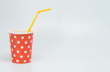 Orange tube in White dot pattern on red paper cup with white background and selective focus