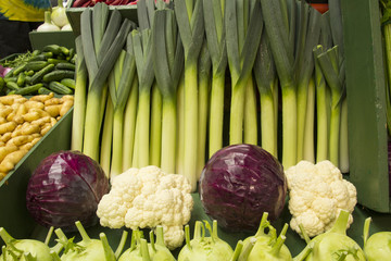 Leeks, purple cabbage, and cauliflower at a farmers' market stand