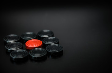 Red pawn chess in group of Black pawn chess with black background and selective focus