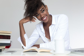 Young African American woman reading book  with a coffee cup on