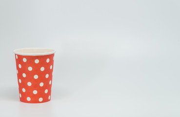 White dot pattern on red paper cup with white background and selective focus