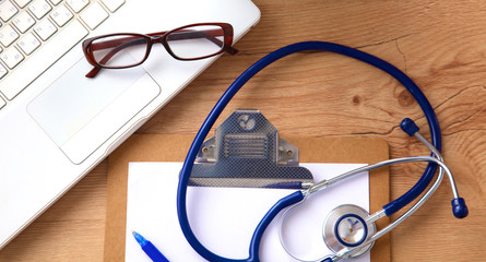 Medical stethoscope lying on a computer keyboard, documents