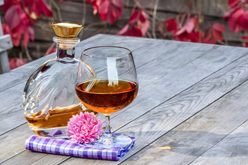 Bottle and a snifter of brandy with flower on the old table