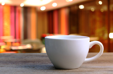 White Coffee cup on wooden table in coffee shop blur background.