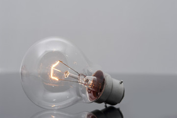 Close up Glowing Light Bulb on Glossy Table