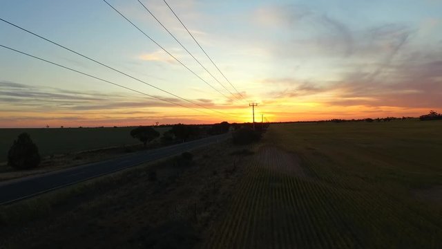 Telegraph Road. Aerial view of outback highway or open road on dusk (sunset) with semi trailer truck, lorry, traveling on rural country route. Telegraph poles, power lines & solitude theme.