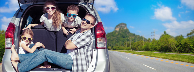 Happy father and children sitting in the car at the sunny day.