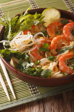 Asian food: soup with shrimps, noodles and herbs close up in a bowl. vertical