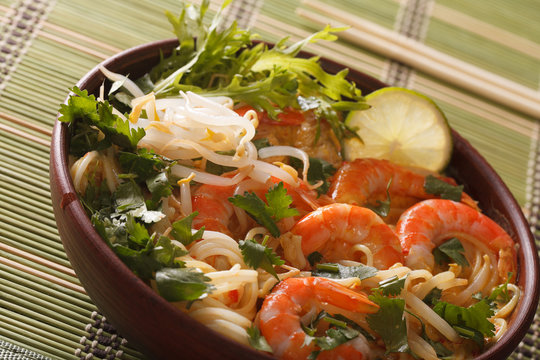 Thick soup with shrimps, noodles and herbs close up in a bowl. horizontal