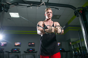 Fototapeta na wymiar A strong man with muscles training on simulators in gym