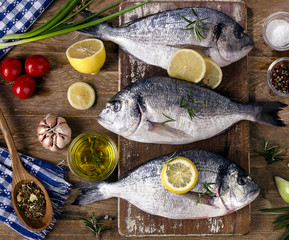 Fresh fish with herbs, spices and vegetables on a rustic wooden