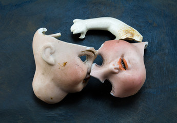 Broken doll parts on grey grunge background