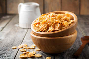 Cornflakes for breakfast in a bamboo plate on old wooden background. Selective focus.