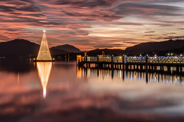 Christmas tree on Lake Woerthersee during colorful sunset. Austria, Carinthia .