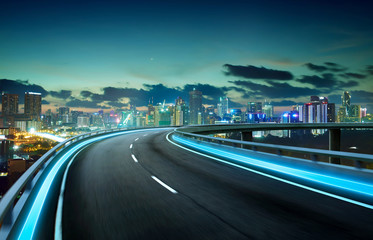 Blue neon light highway overpass motion blur with city  skyline background , night scene .