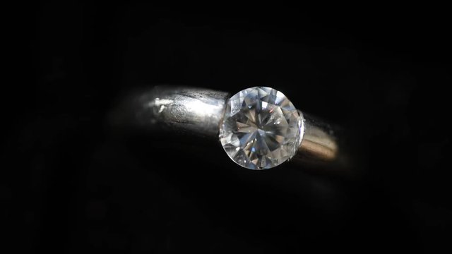 Platingring mit gro&szlig;em Solit&auml;r-Diamanten vor schwarzem Hintergrund, drehend, Draufsicht