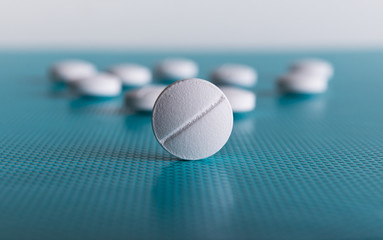White medical pill on blue background, macro.