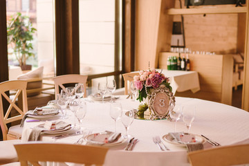 Table setting at wedding reception. Wedding floral decoration and stylized table number on guest table.