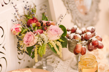 flower composition and grapes in vintage vase as a decoration of wedding candy bar