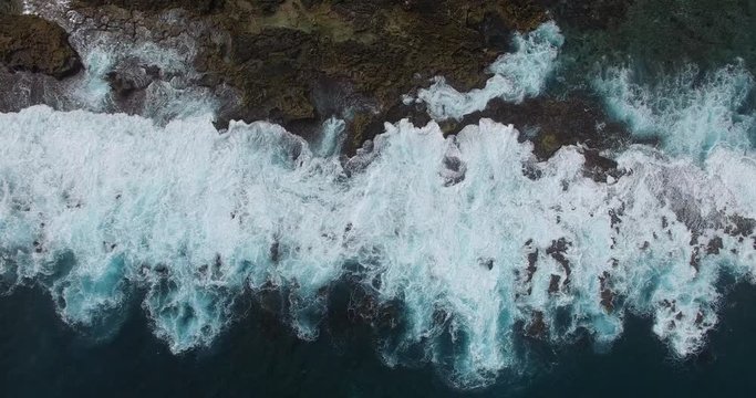 A vertical aerial of big swells breaking againt a rugged rocky shore  at  Shark Bay in Western Australia